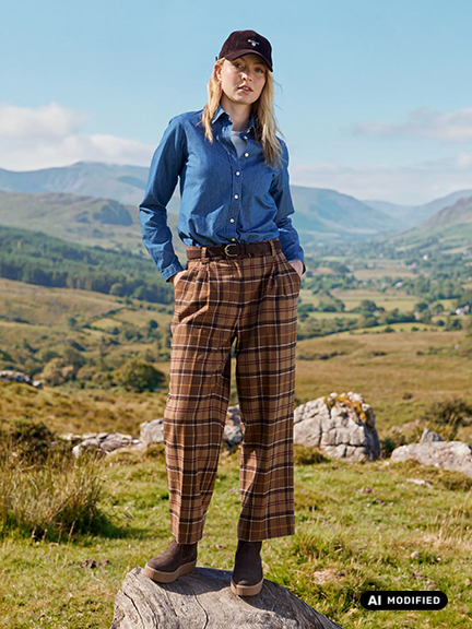Frau in Tartan-Hose steht auf Holzstamm