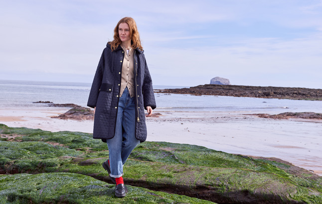 Frau im langen Steppmantel von Barbour am Meer