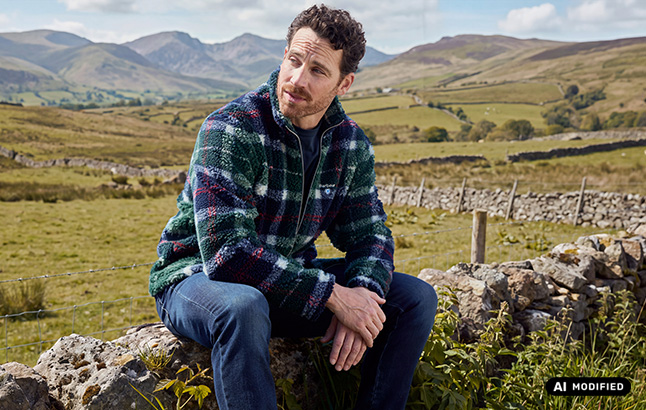 Mann in Teddy-Tartan-Jacke vor Highland-Kulisse