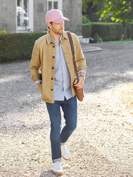 Mann im Overshirt mit Ledertasche und Cap
