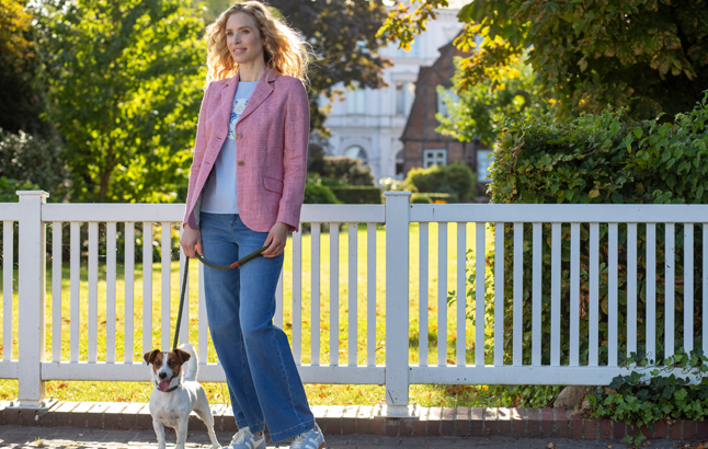 Frau im rosa Blazer mit Hündchen an der Leine