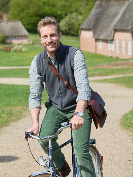 Mann auf Fahrrad in Charles Robertson Outfit
