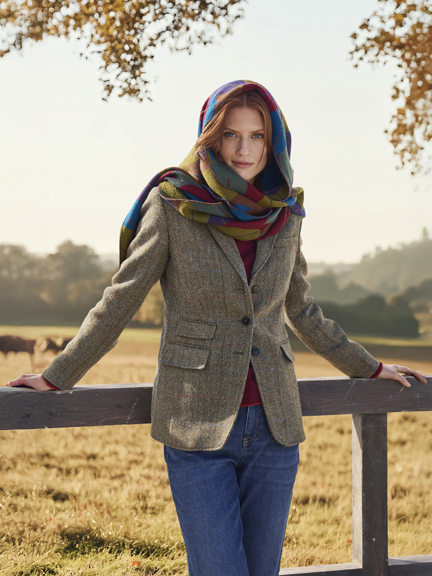 Frau am Zaun in Tweedjacke mit Schal