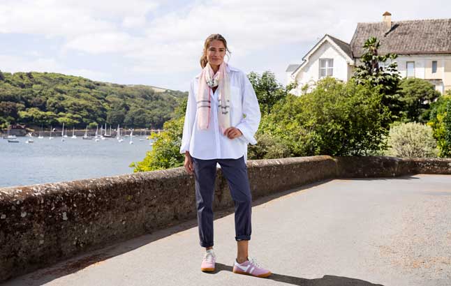 Frau in weißer Leinenbluse vor Bucht