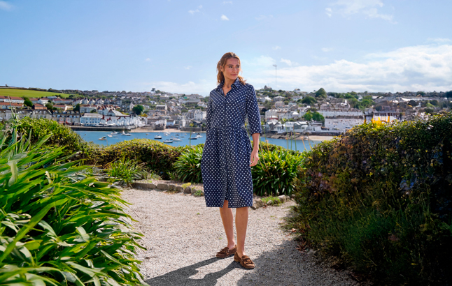 Frau im gepunkteten Kleid vor Cornwall-Kulisse