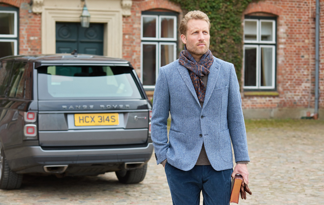 Mit am blauen Tweedsakko vor Geländewagen