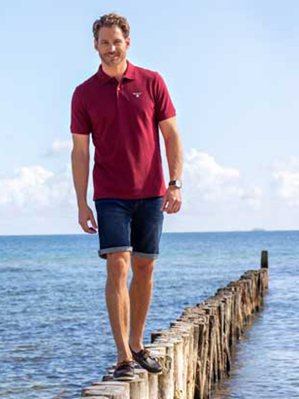 Mann in Polo und Shorts auf Wellenbrechern