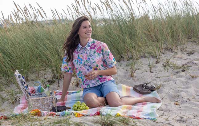 Frau im Sommeroutfit beim Picknick am Strand
