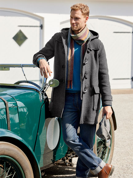 Mann im Dufflecoat lehnt an Oldtimer