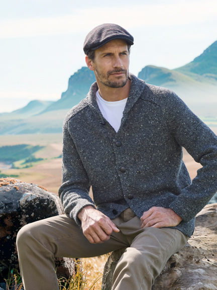 Mann sitzt auf Stein in karger Landschaft