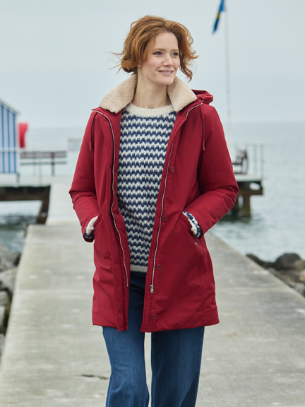 Frau Auf Pier mit rotem Wintermantel